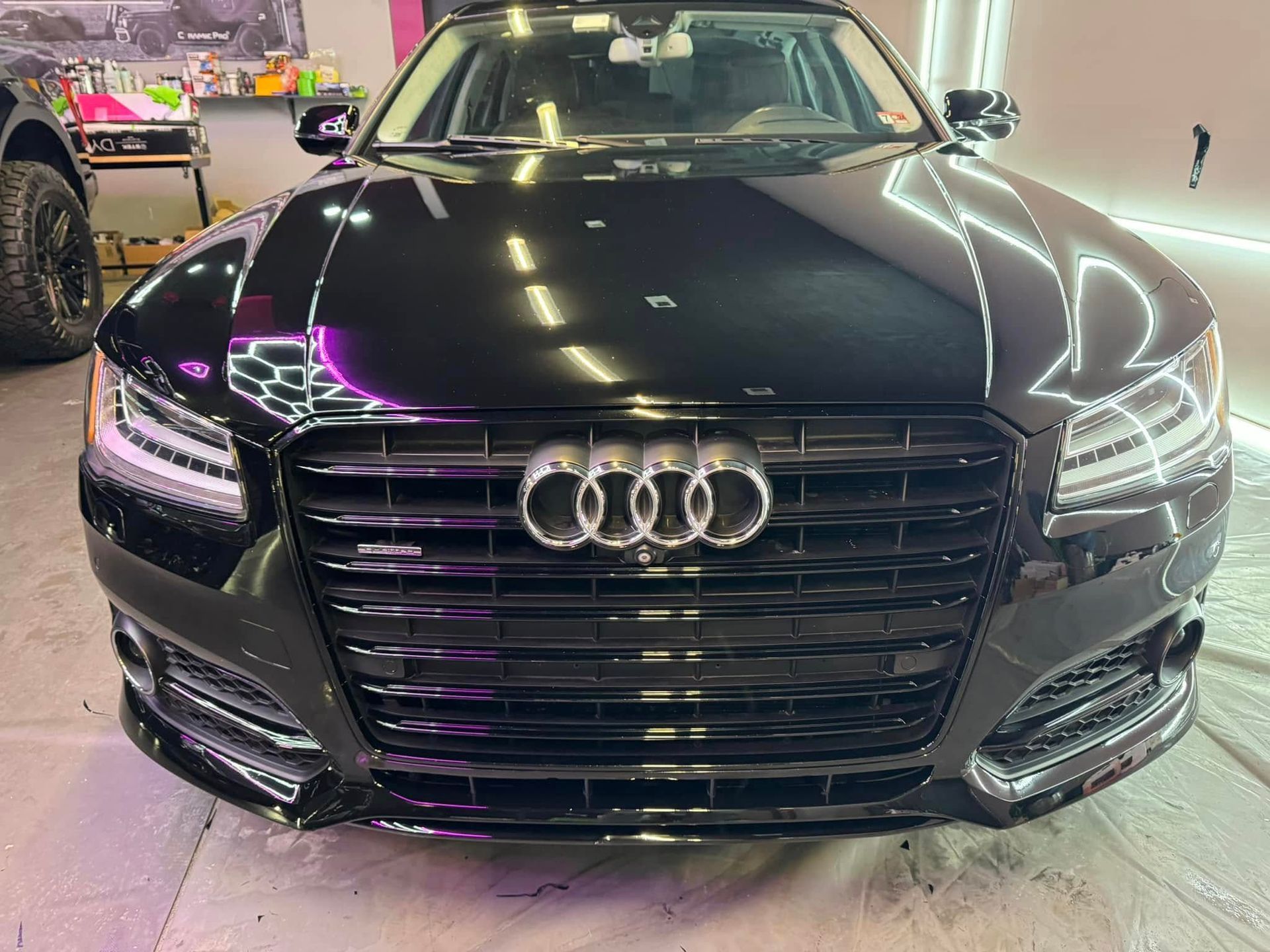Black Audi sedan with shiny finish, centered view, parked indoors.