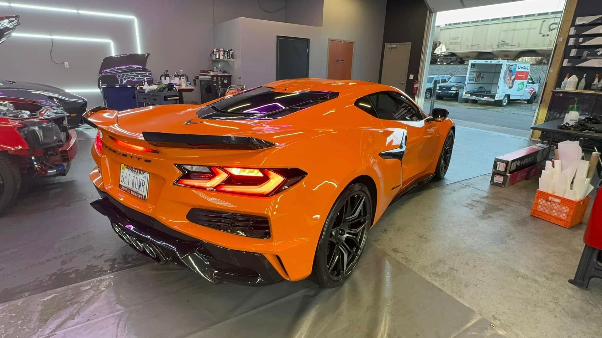 Orange sports car parked inside a garage, license plate visible.
