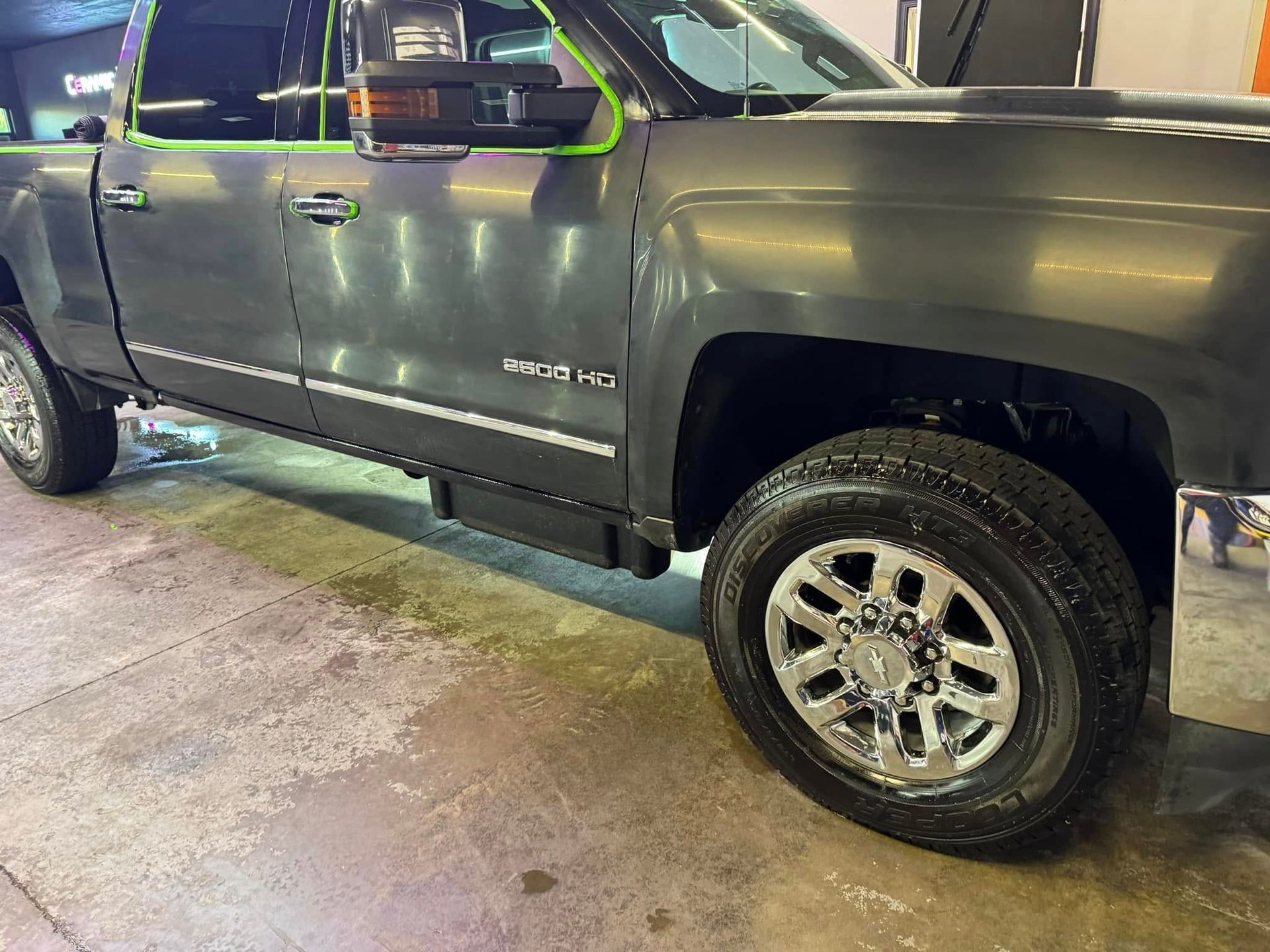 Dark gray pickup truck with chrome wheels parked on a concrete surface.
