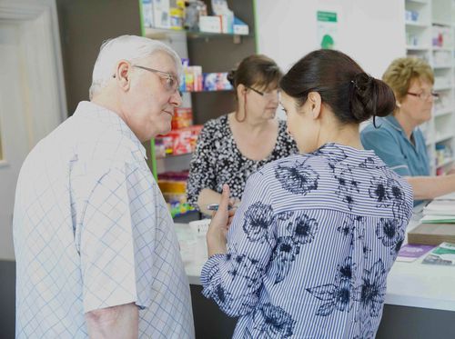 A man and a woman are talking to each other in a pharmacy.