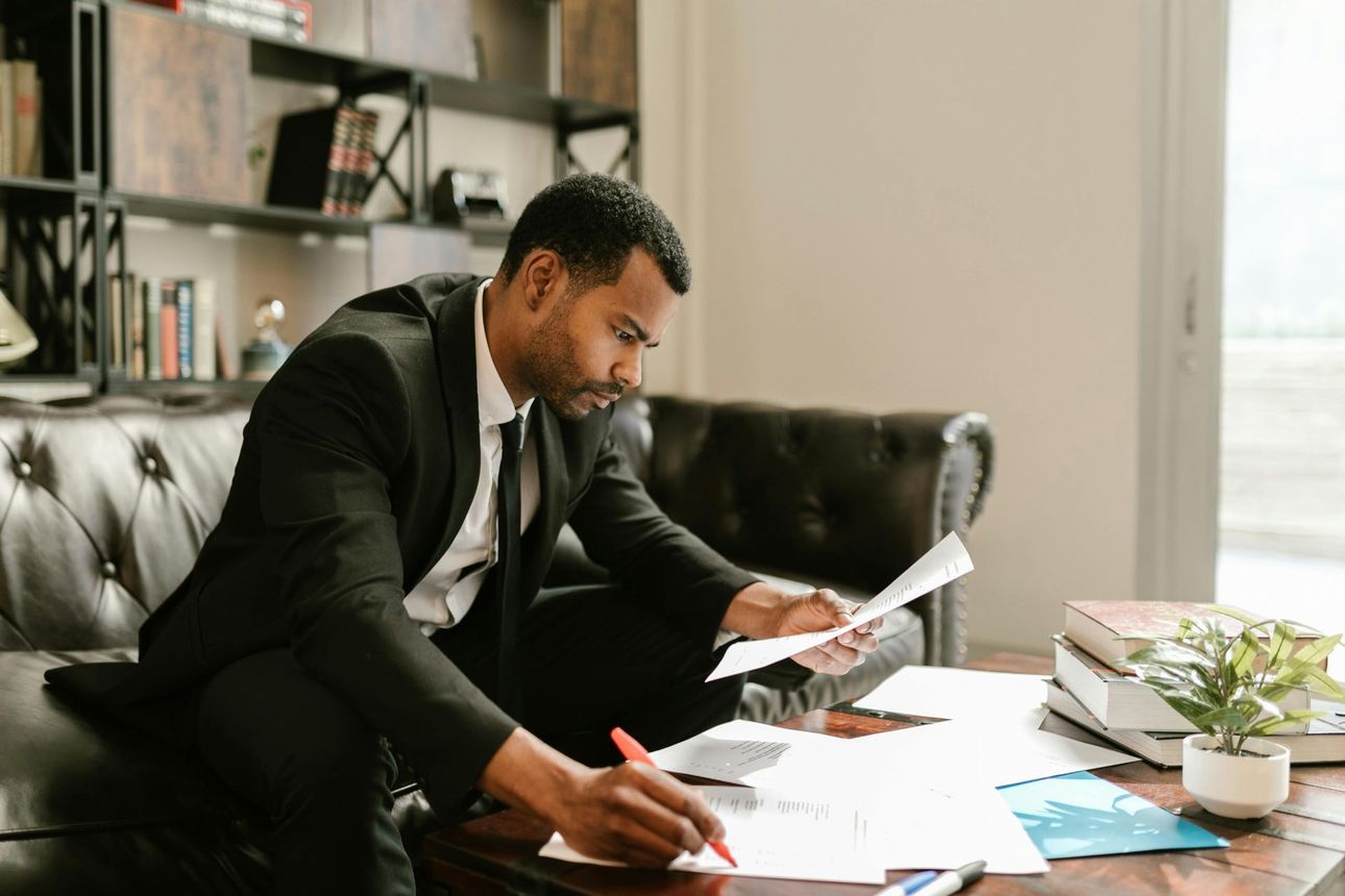 Man in a suit reviewing papers at a desk in a modern office