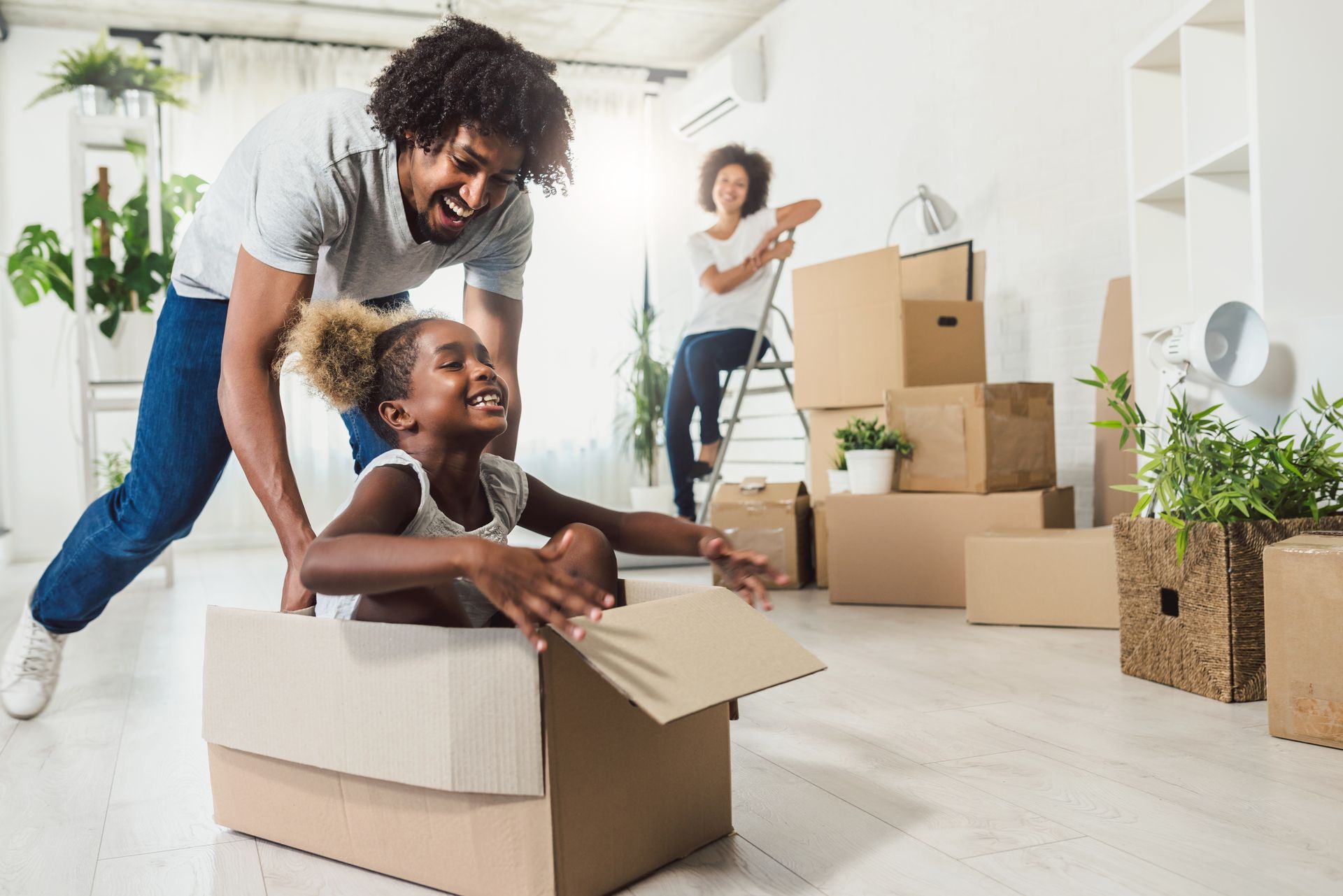 A man and a little girl are playing in a cardboard box in a living room.