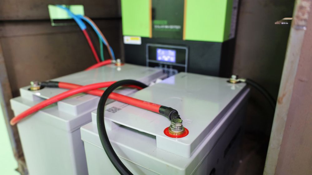 Two Batteries Are Connected To A Green Device — Anthony Cameron Electrical & Solar in Kepnock, QLD