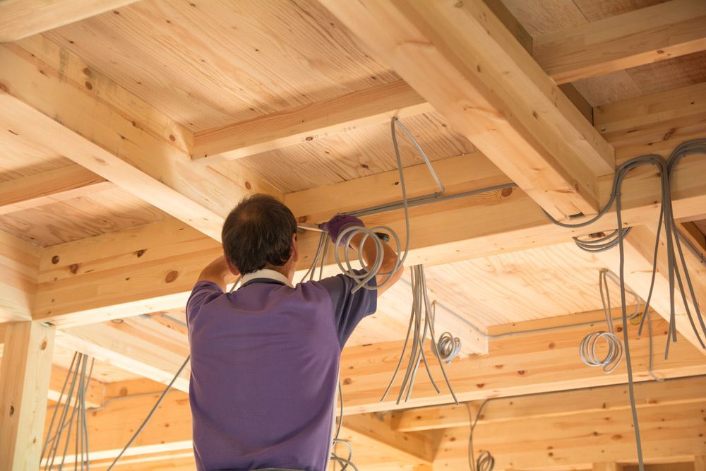 Man In A Purple Shirt Is Working On A Wooden Structure — Anthony Cameron Electrical & Solar in Kepnock, QLD