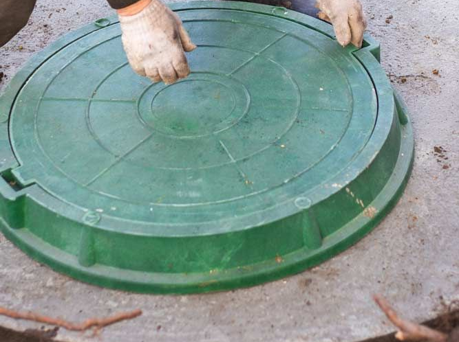A man opening the lid of a septic tank.