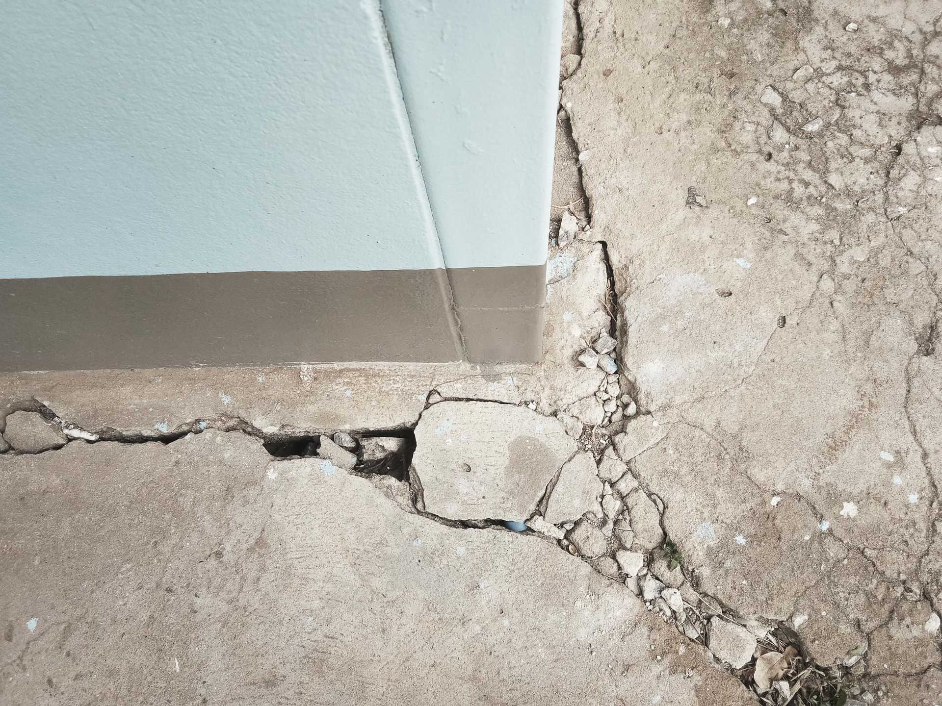 a cracked concrete floor next to a wall