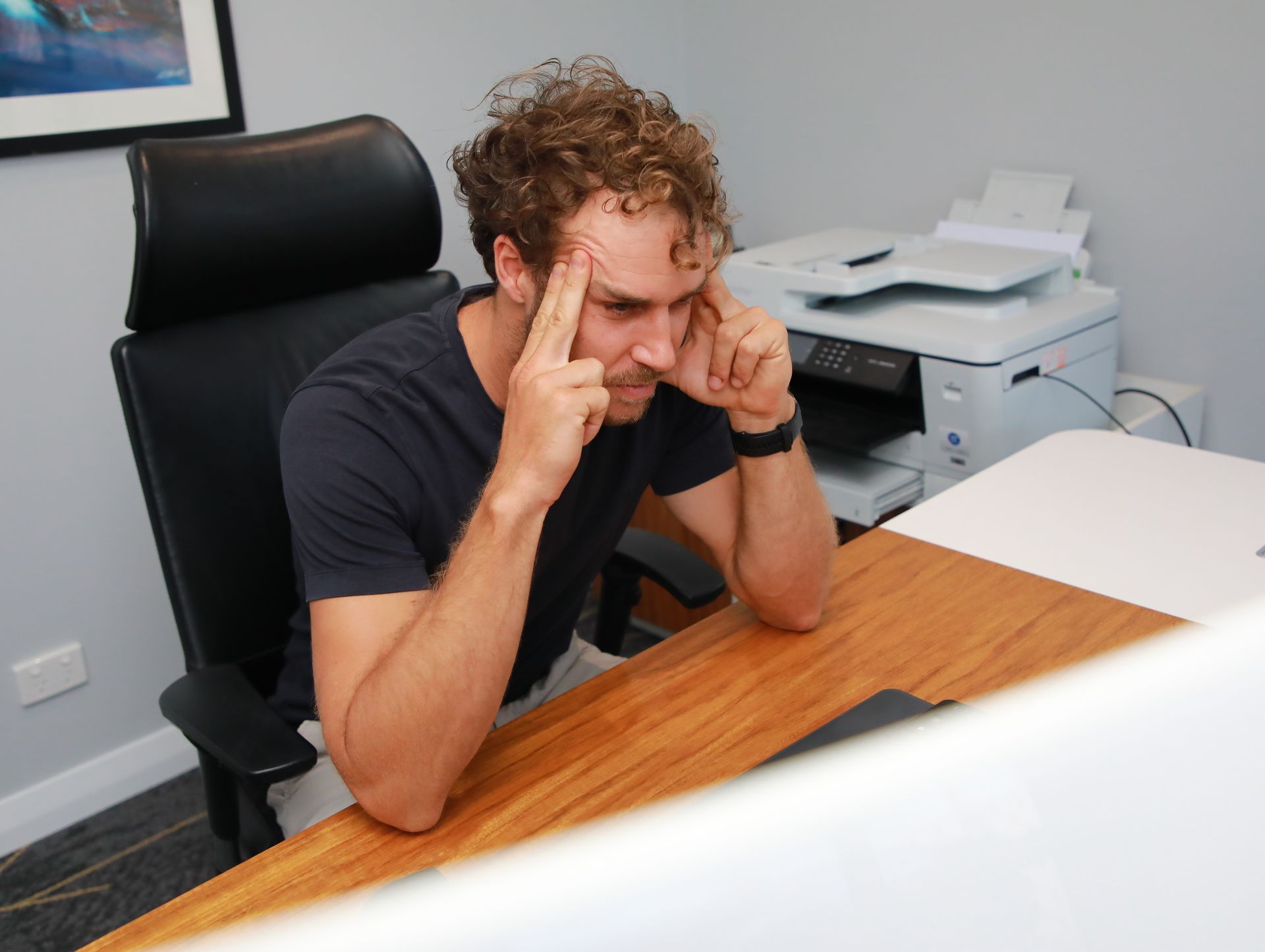 A man sitting at a desk with his hands on his head