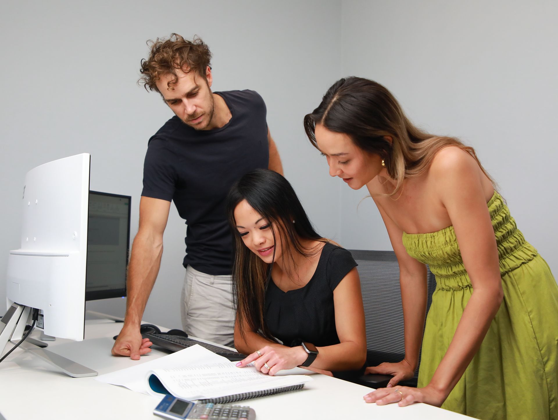 A man and two women are looking at a computer screen.