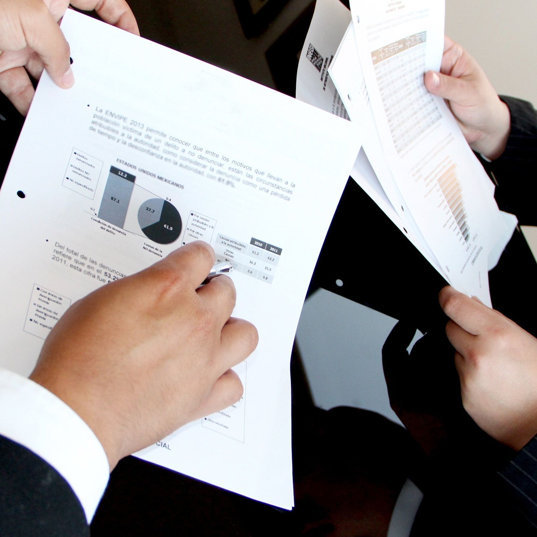 A person is holding a piece of paper with a pie chart on it