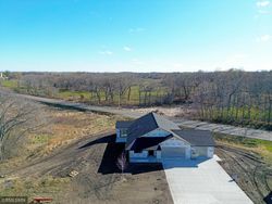 An aerial view of a house sitting on top of a dirt field next to a road.