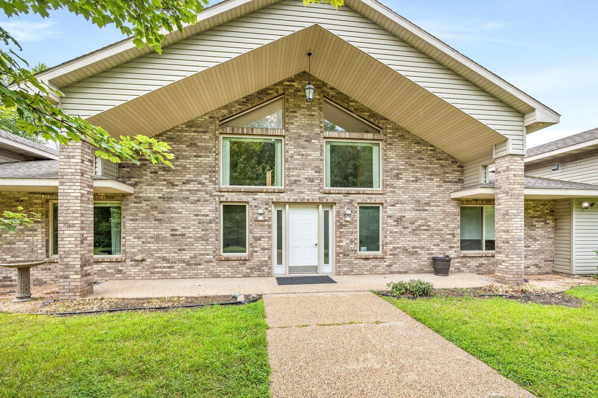 A large brick house with a white door and a walkway leading to it.