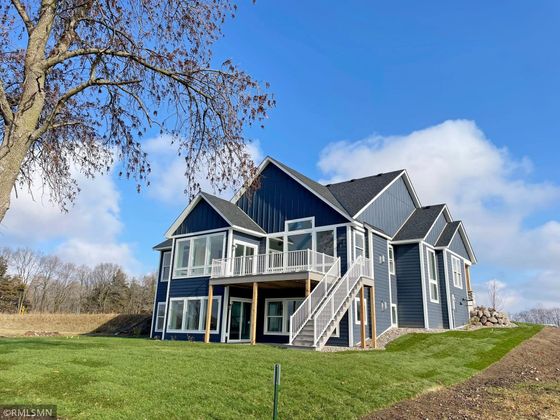 A large house with a lot of windows is sitting on top of a lush green hill.