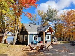 A small blue house with a porch and chairs in front of it.