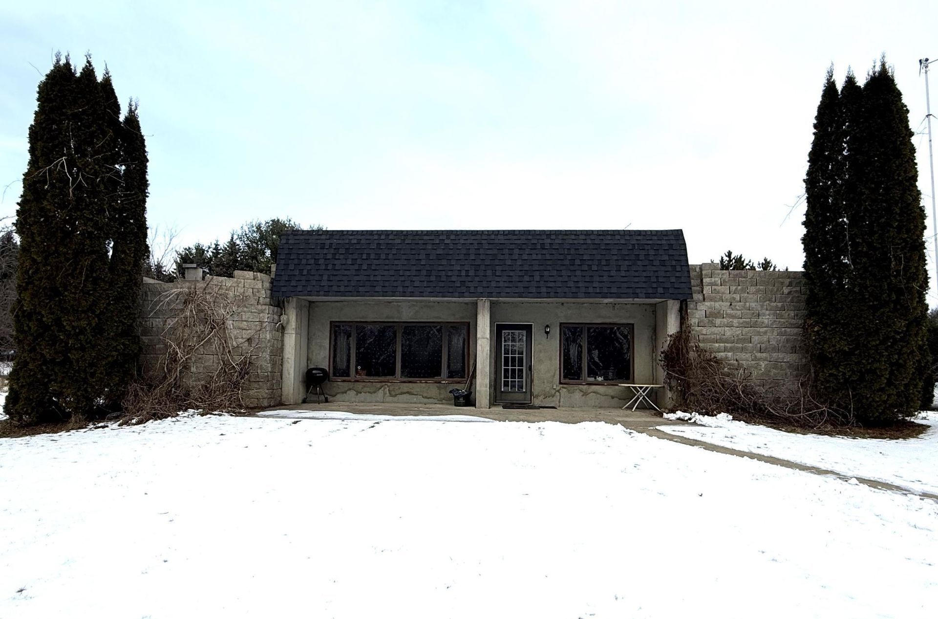 A house with a blue roof is surrounded by snow and trees