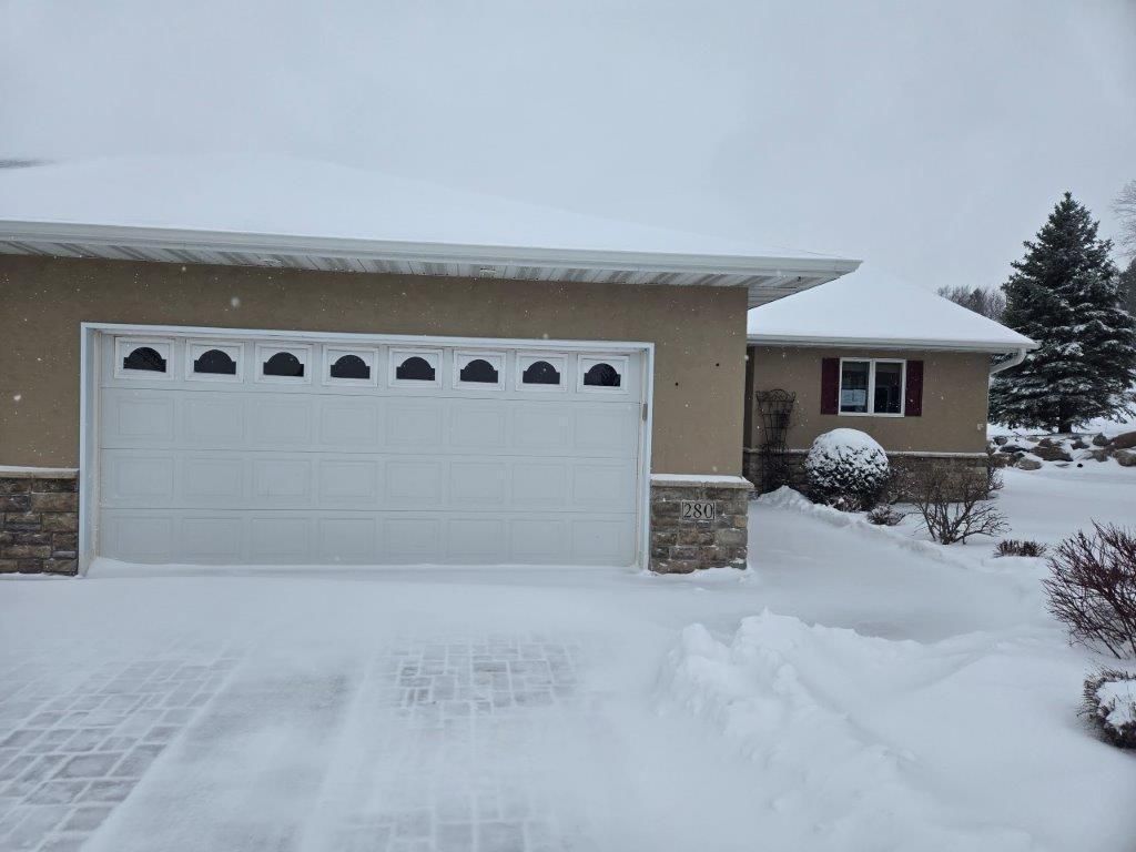 A garage door is covered in snow in front of a house.