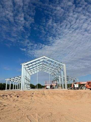 Steel frame building under construction, against a partly cloudy blue sky.