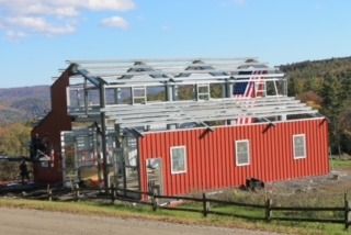 Red building under construction with glass and metal framework on a hillside.