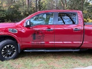 Red pickup truck with company logo on the side, parked outdoors.