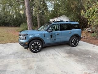 Blue Ford Bronco Sport SUV parked on a concrete surface with roof rack.