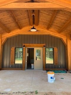 Exterior view of a building with a wood-beam porch, doors, windows, and decorative shutters.
