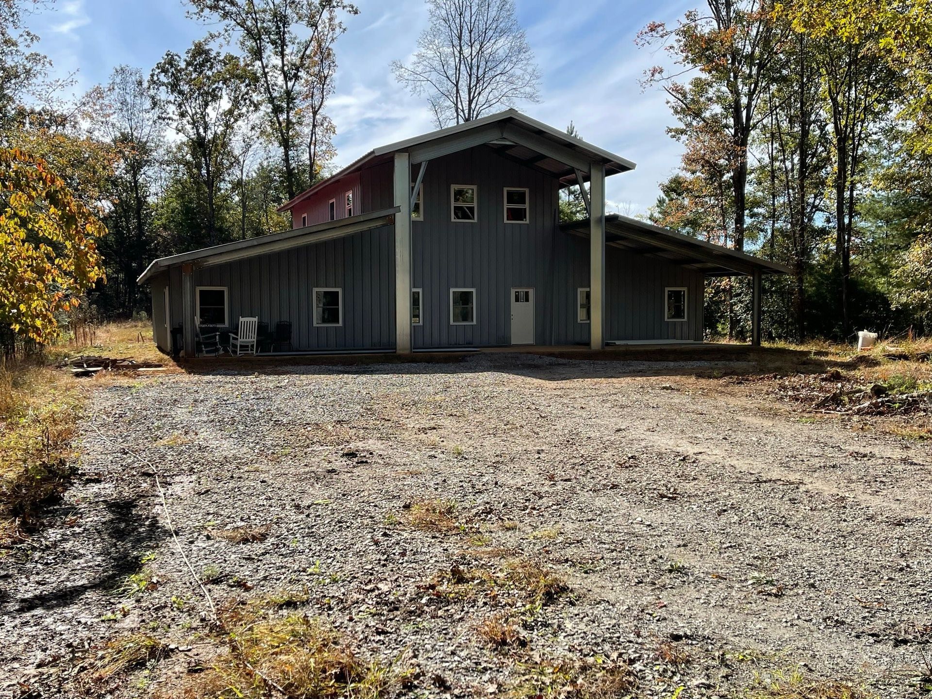 Gray house with gravel driveway, surrounded by trees
