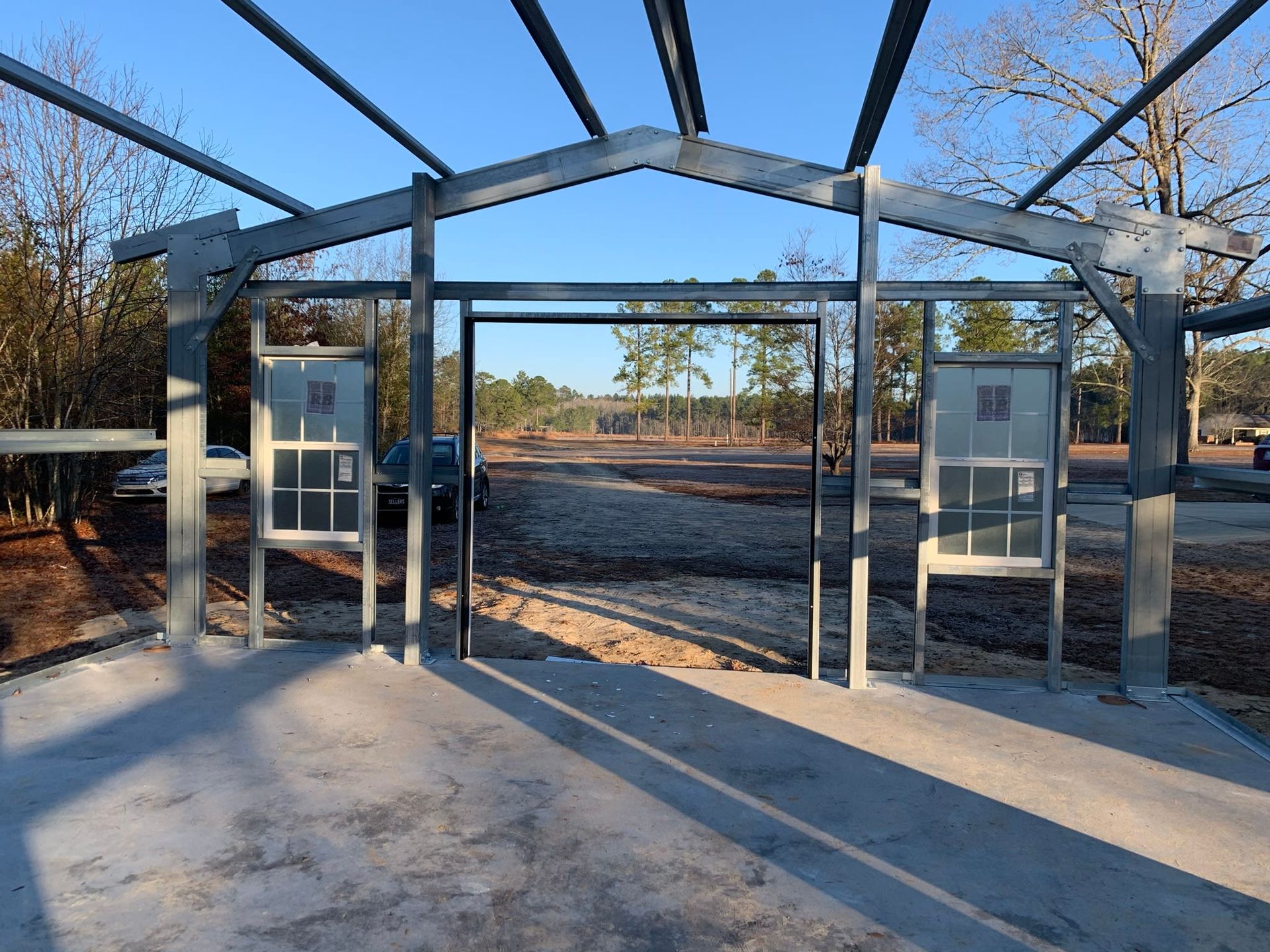 Steel frame building under construction with windows, open doorway, and concrete floor