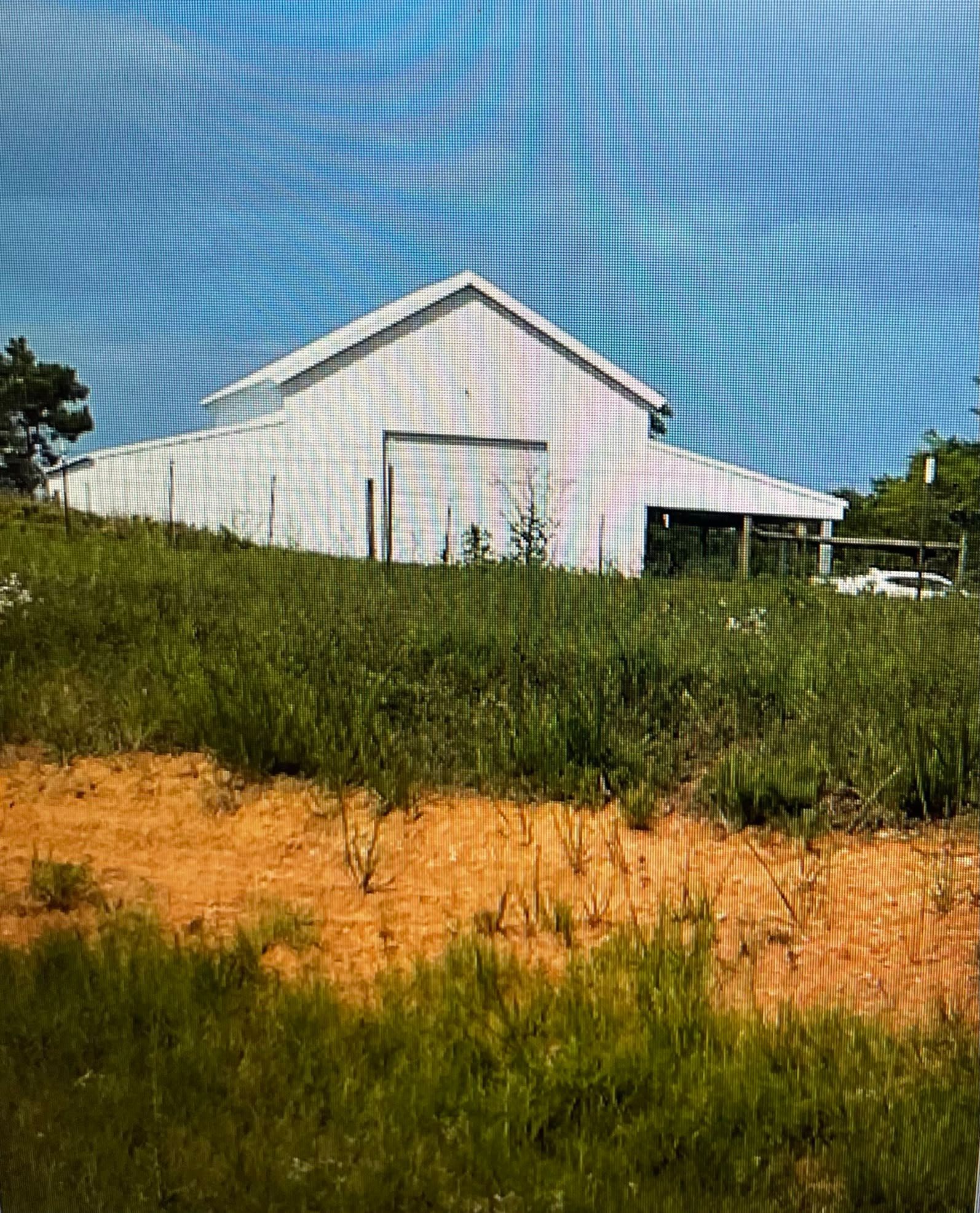 White barn on a grassy hill with a blue sky in the background