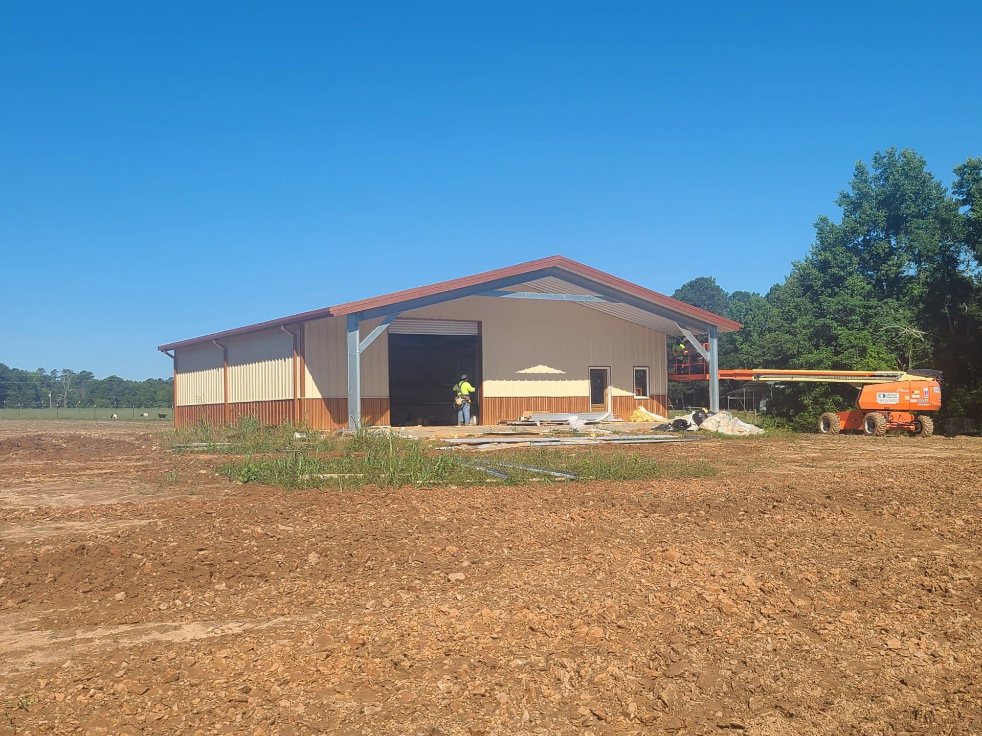 New tan and brown metal building under construction on a clear day
