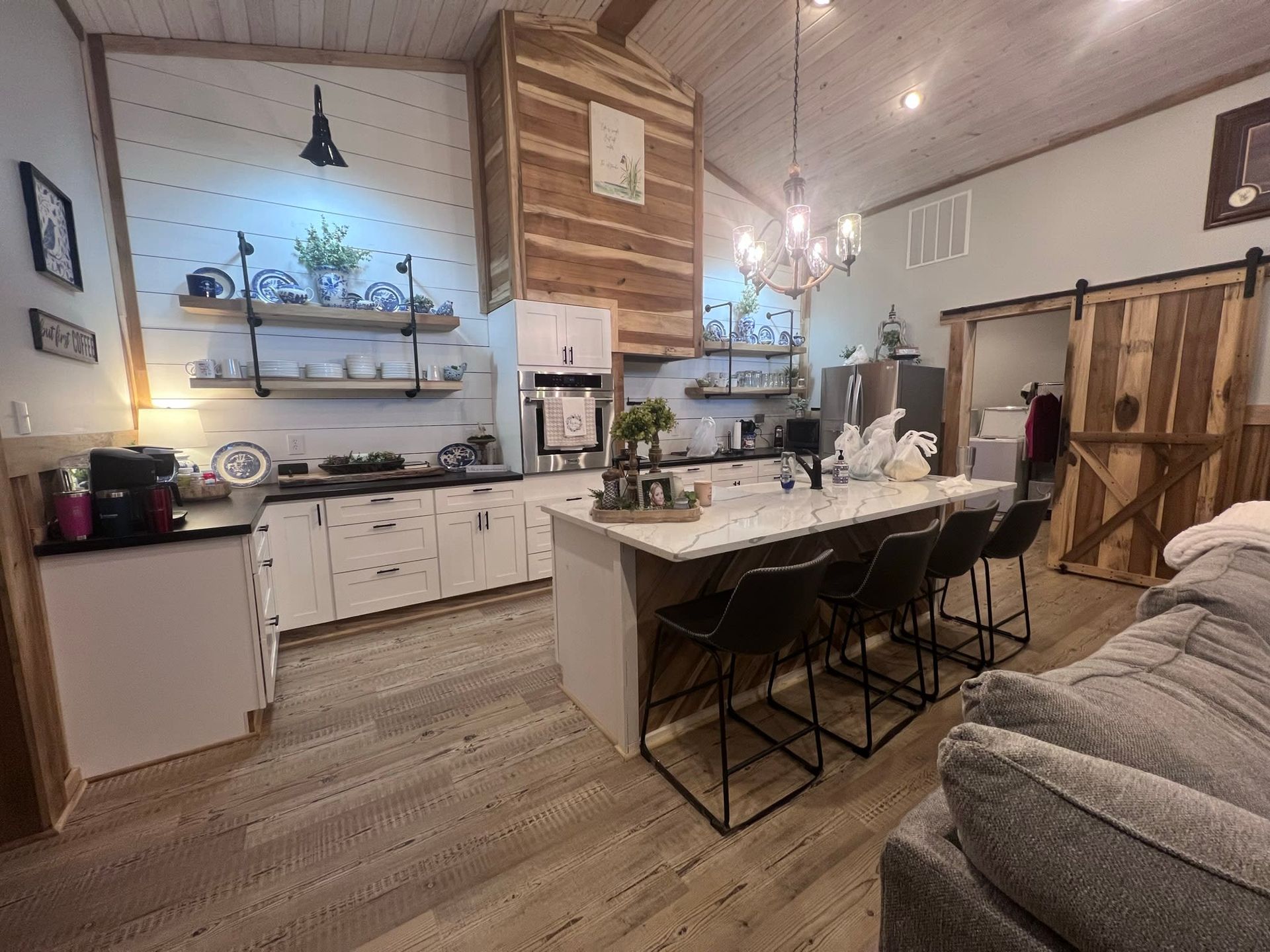 Kitchen with white cabinets, island with bar stools, wood accents, and a chandelier