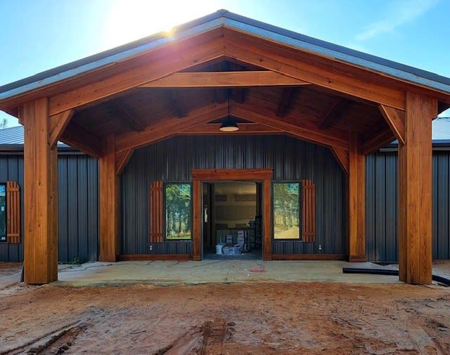 Wooden porch with dark gray building. Sunlight shines on the entrance