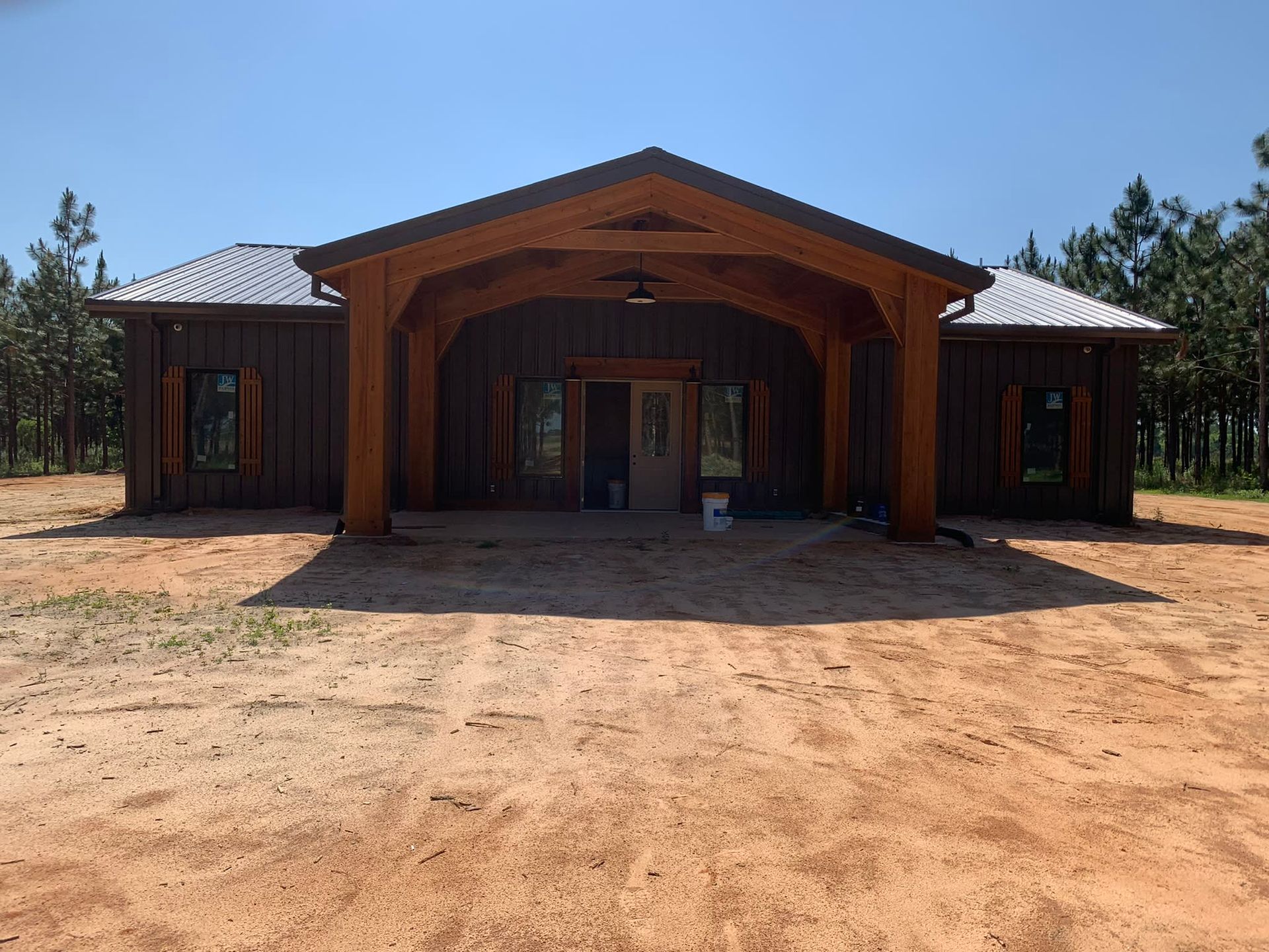 Brown wooden house with an entryway, set in a clearing with a blue sky above