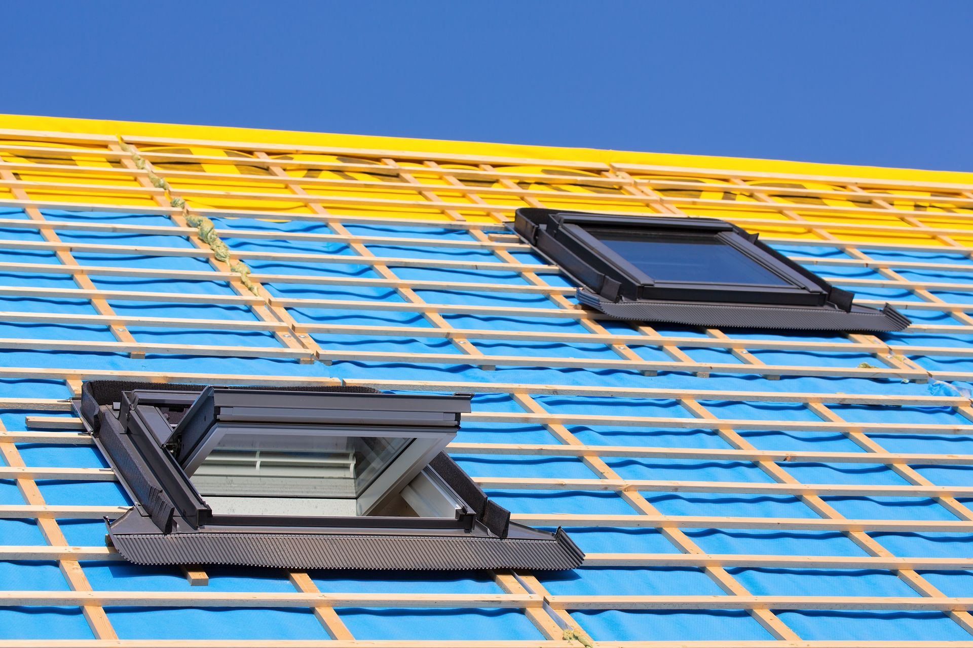 Two skylights are being installed on a roof under construction