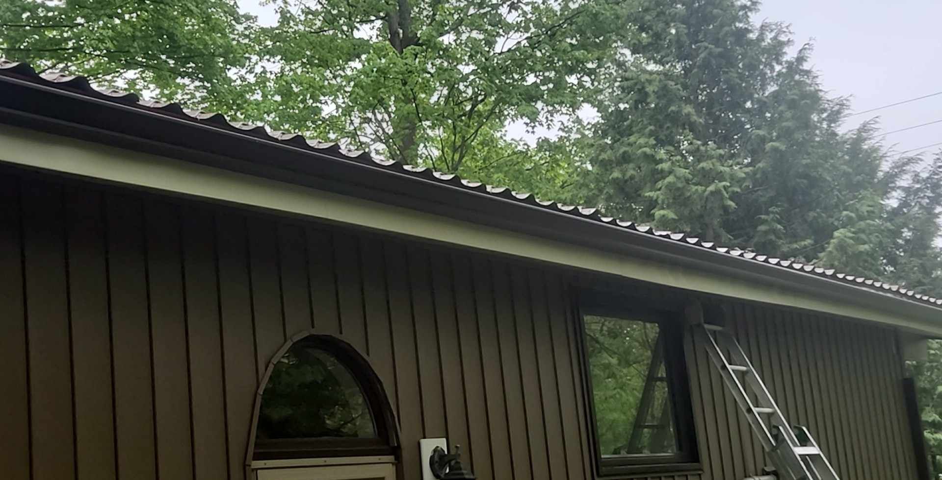 A brown house with a ladder on the side of it.