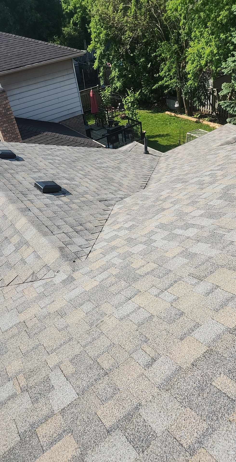 A close up of a roof with a garage in the background.