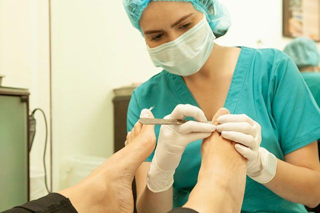 Una enfermera corta las uñas de los pies de un paciente con unas tijeras.