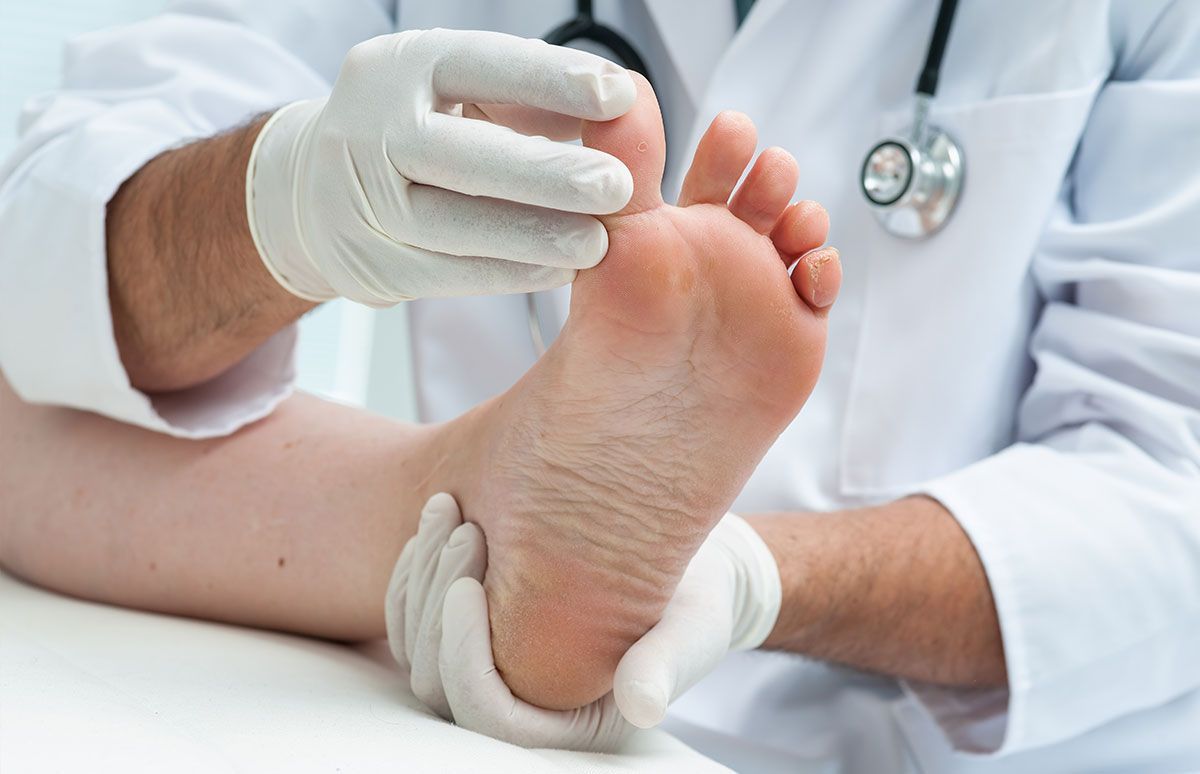 Un médico examina el pie de un paciente con un estetoscopio.