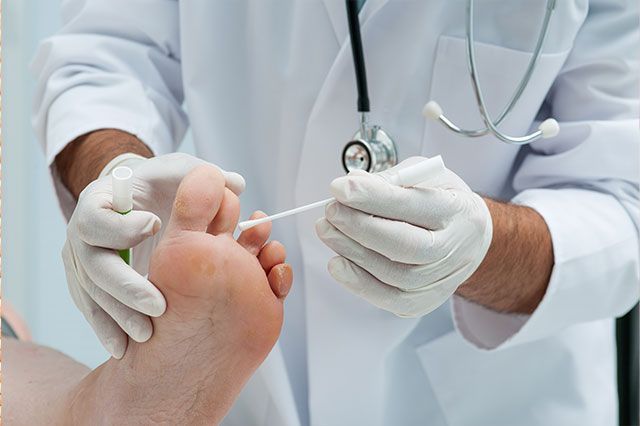 Un médico examina el pie de un paciente con un hisopo de algodón.