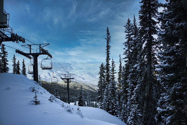 A ski lift is going up a snowy mountain surrounded by snow covered trees.