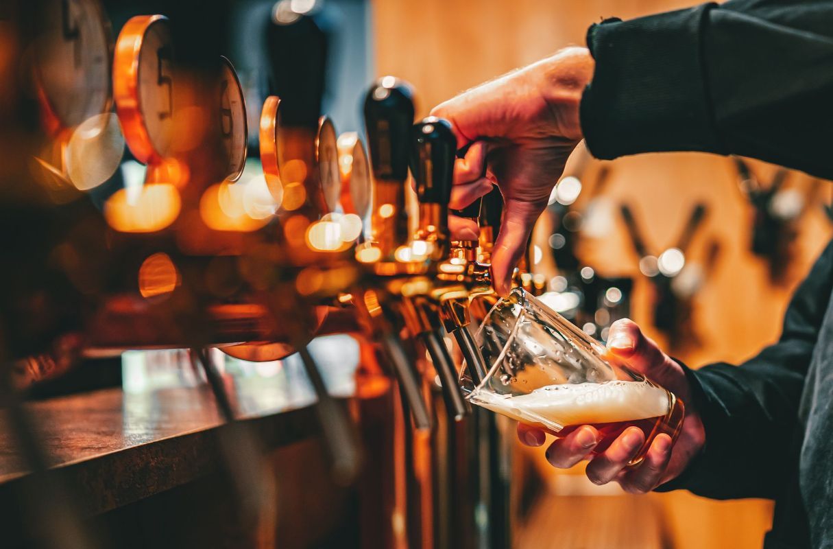 A person is pouring beer into a glass at a bar.