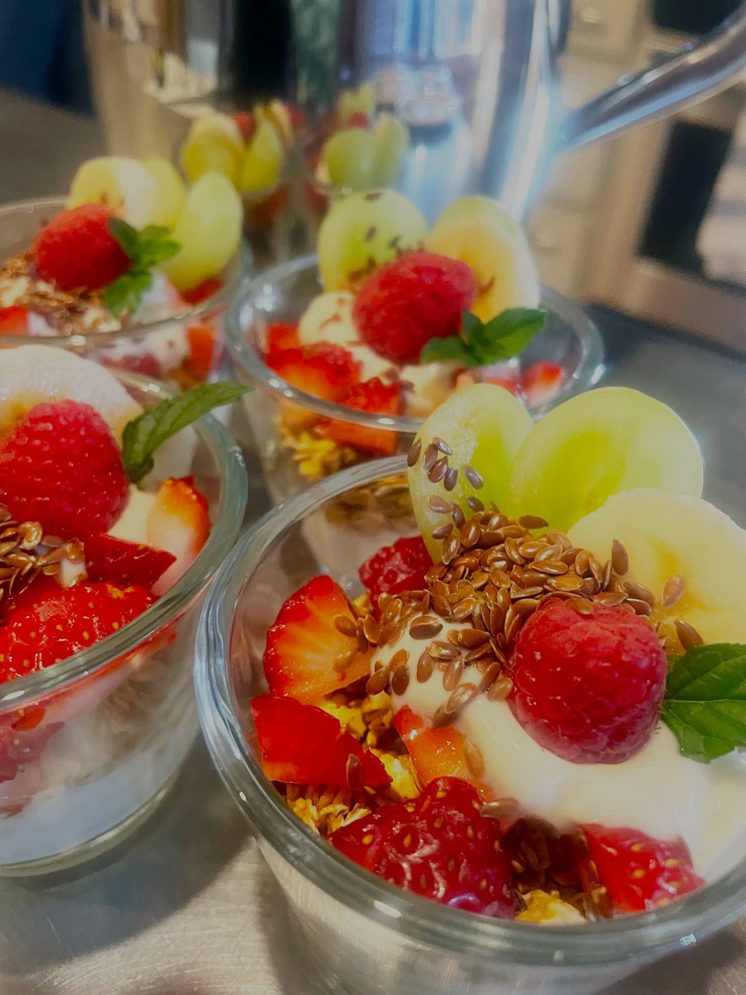 A close up of three bowls of fruit and yogurt on a table.