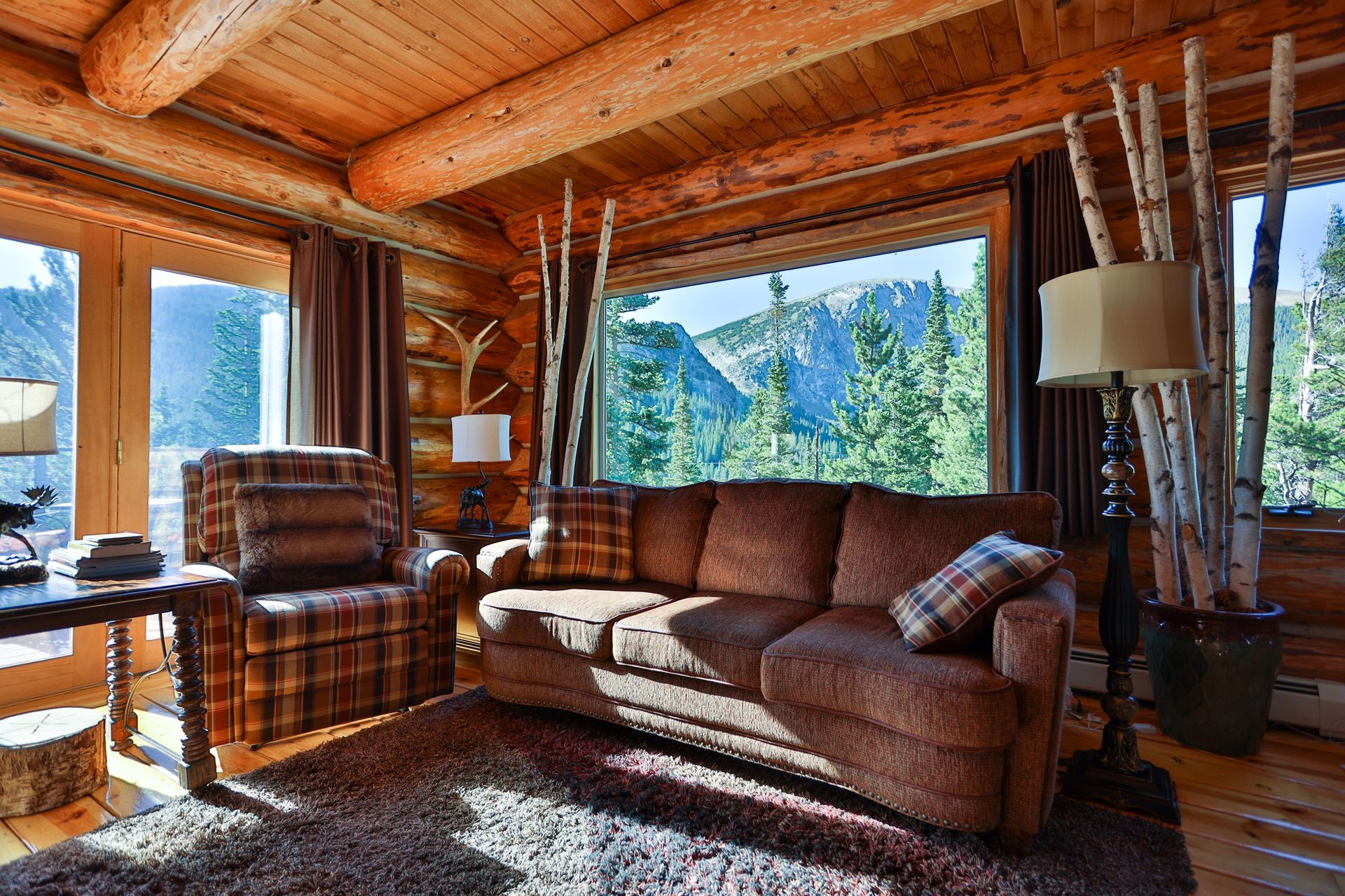 A living room in a log cabin with a couch and chairs.