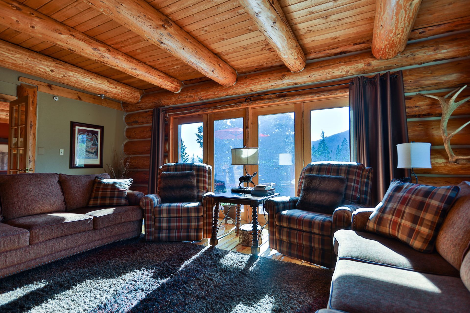 A living room in a log cabin with a couch and chairs