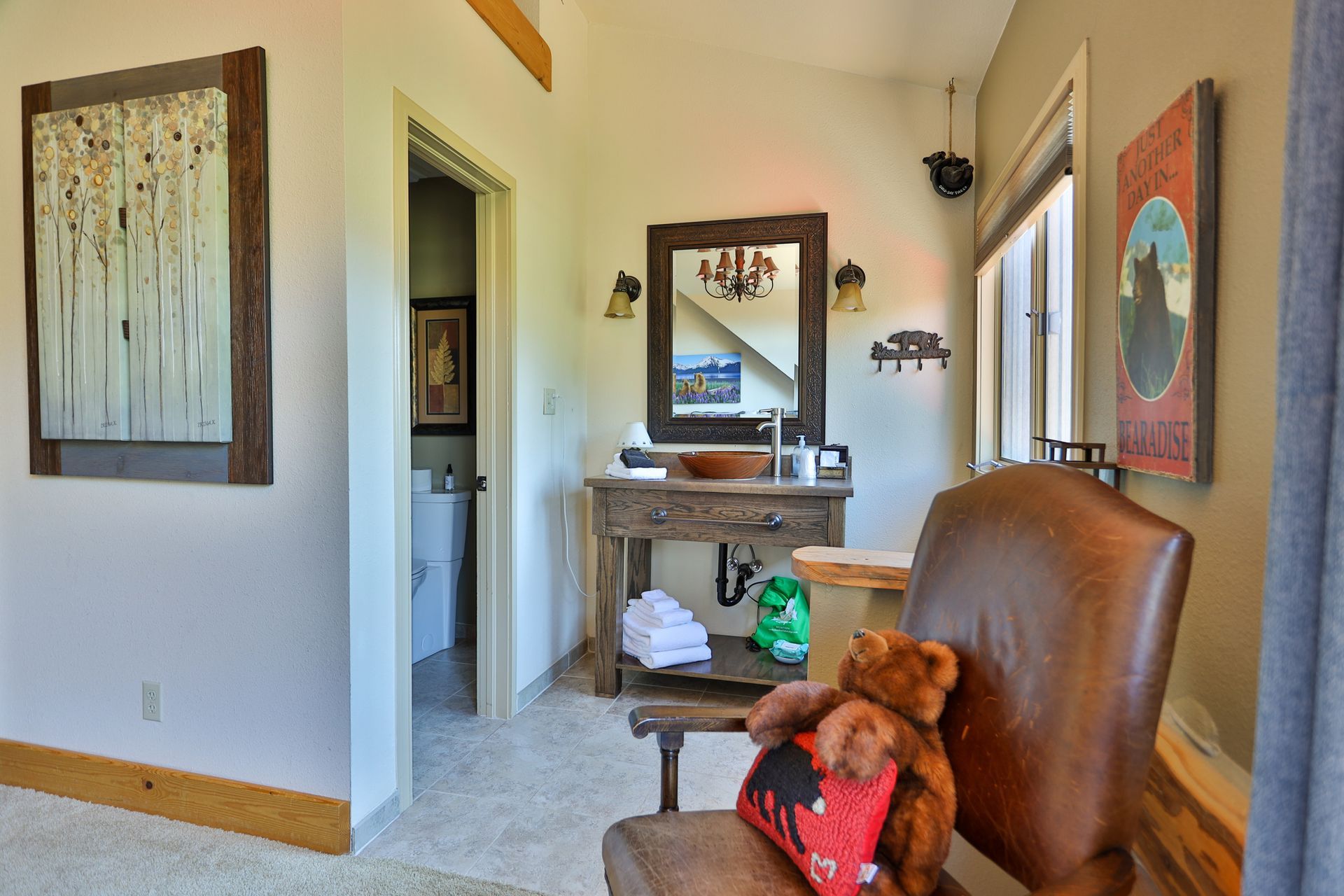 A teddy bear is sitting in a chair in a bathroom next to a sink.