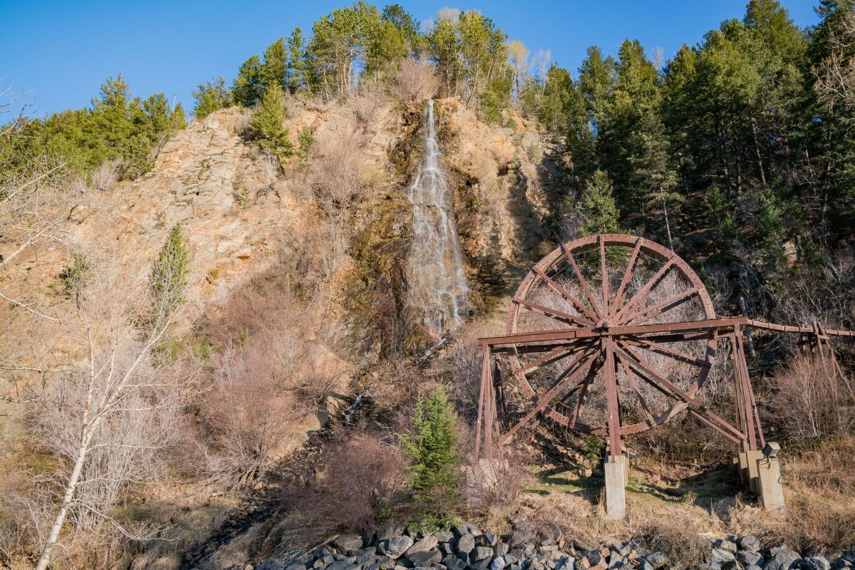 There is a waterfall in the background and a water wheel in the foreground.