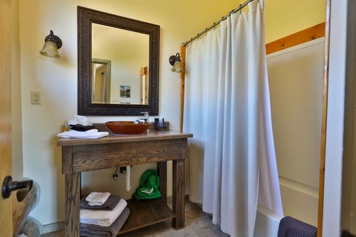 A bathroom with a sink , mirror and shower curtain.