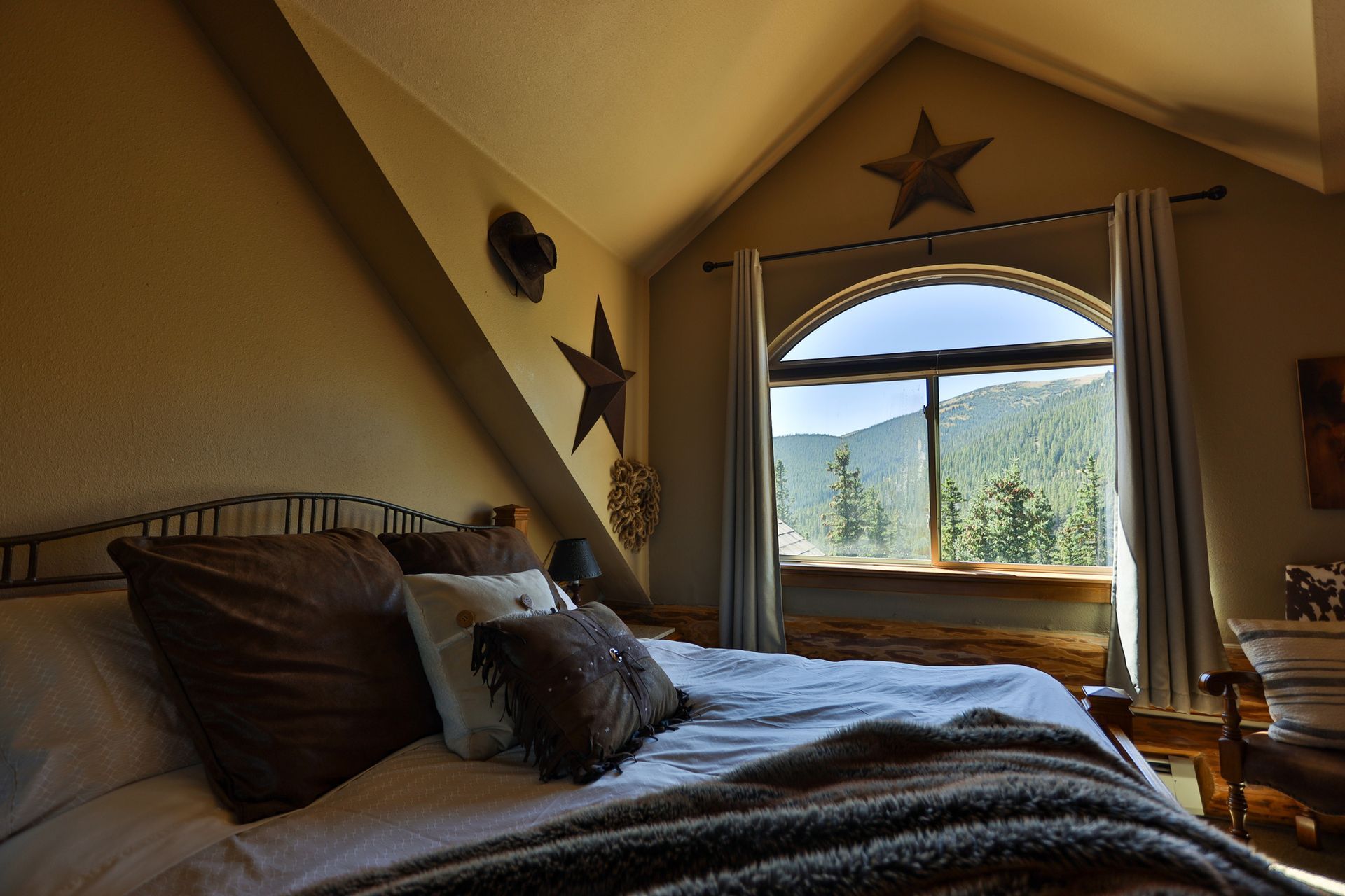 A bedroom with a bed and a window with mountains in the background