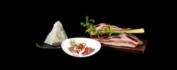 Vari salumi esposti su assi di legno su uno sfondo scuro.