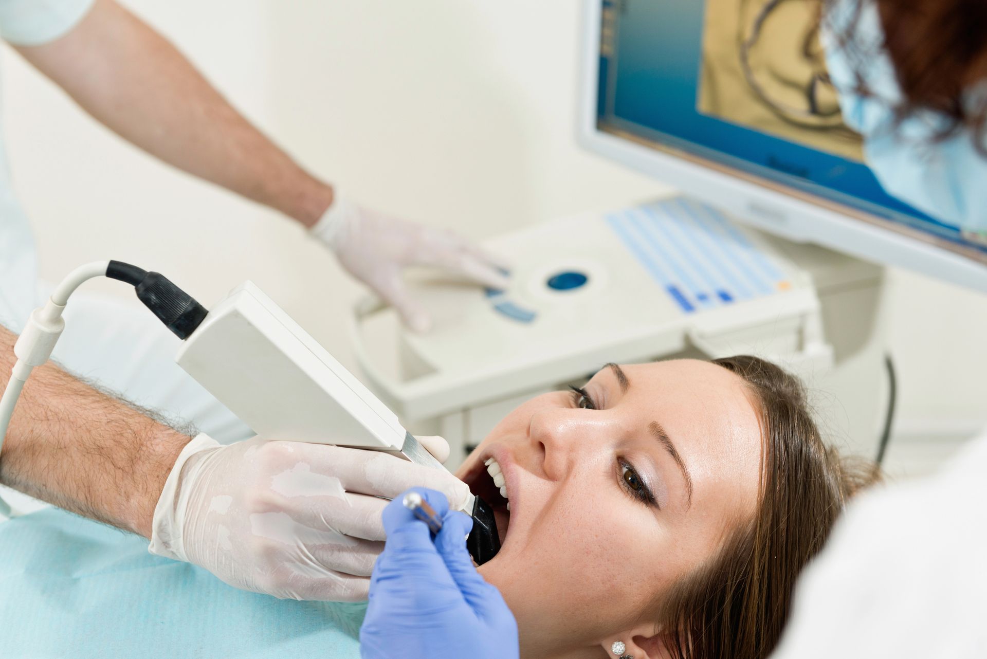 Dentista examinando la boca de un paciente con guantes en una sala de examen clínico.