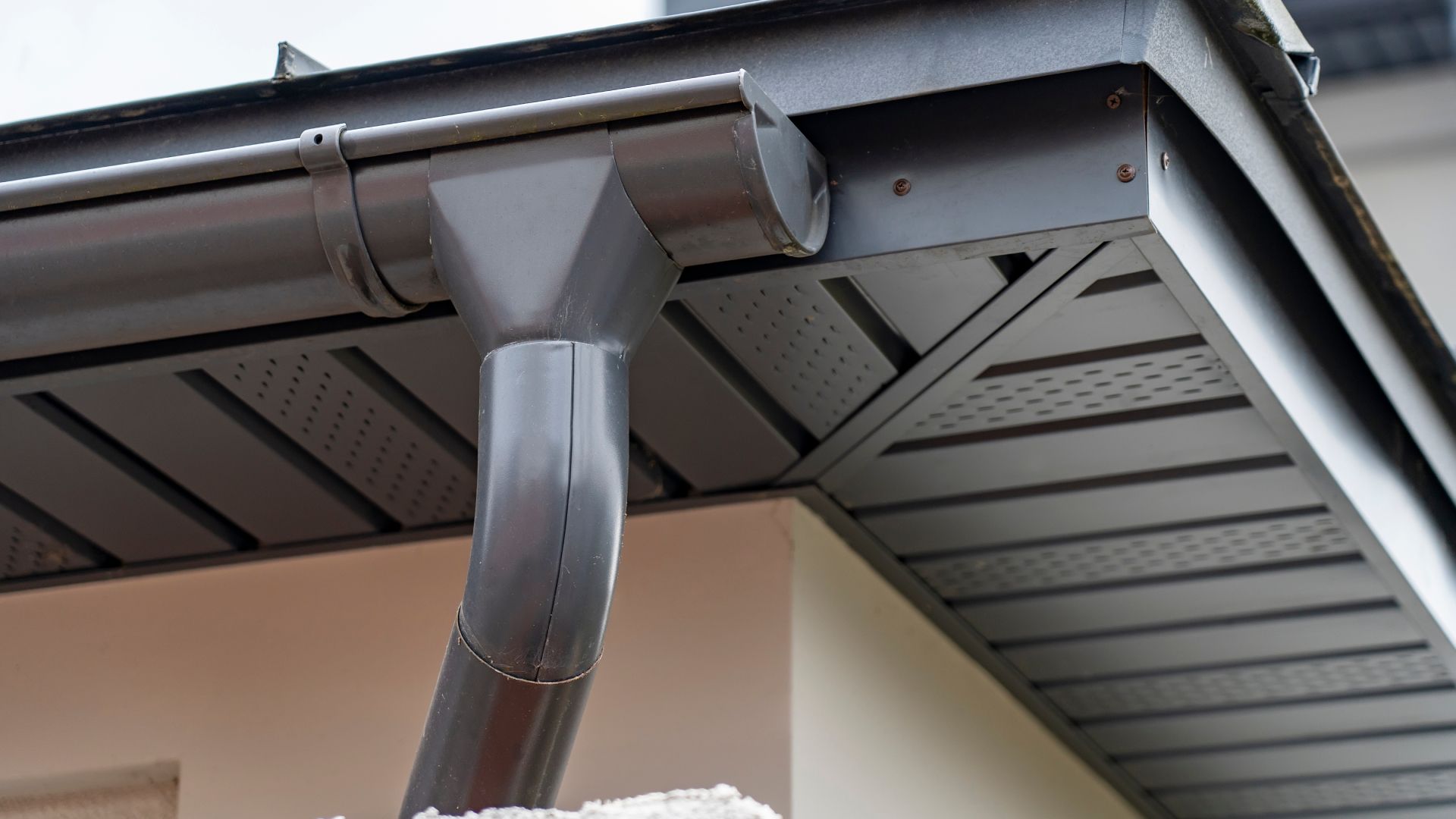 A close up of a gutter on the side of a house.