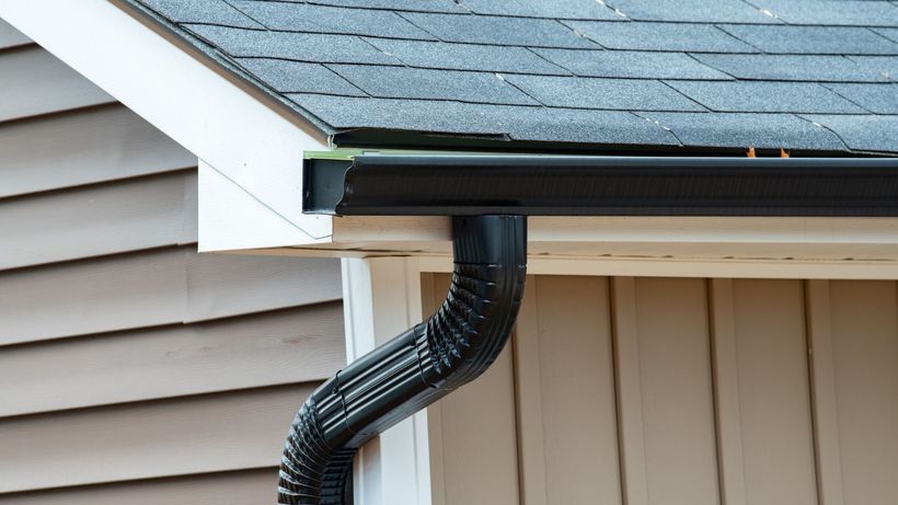 A close up of a black gutter on the side of a house.